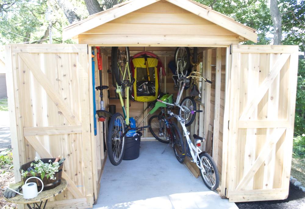 Bikes, and other recreational gear are neatly arranged in a wood storage shed.