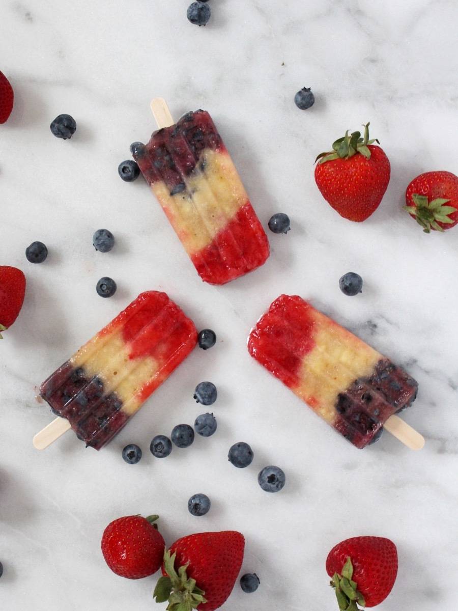 Ice treats sit on a surface with berries.