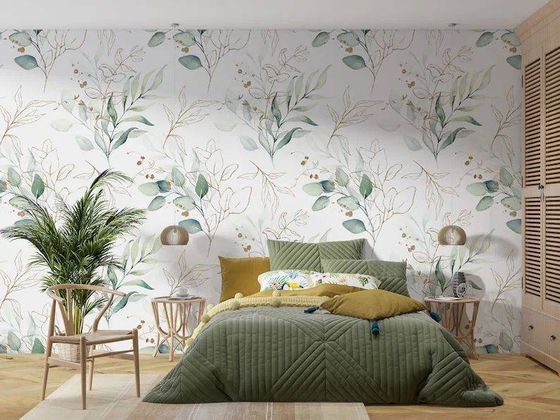 Green leaves floral wallpaper behind bed with green comforter and brown end table.